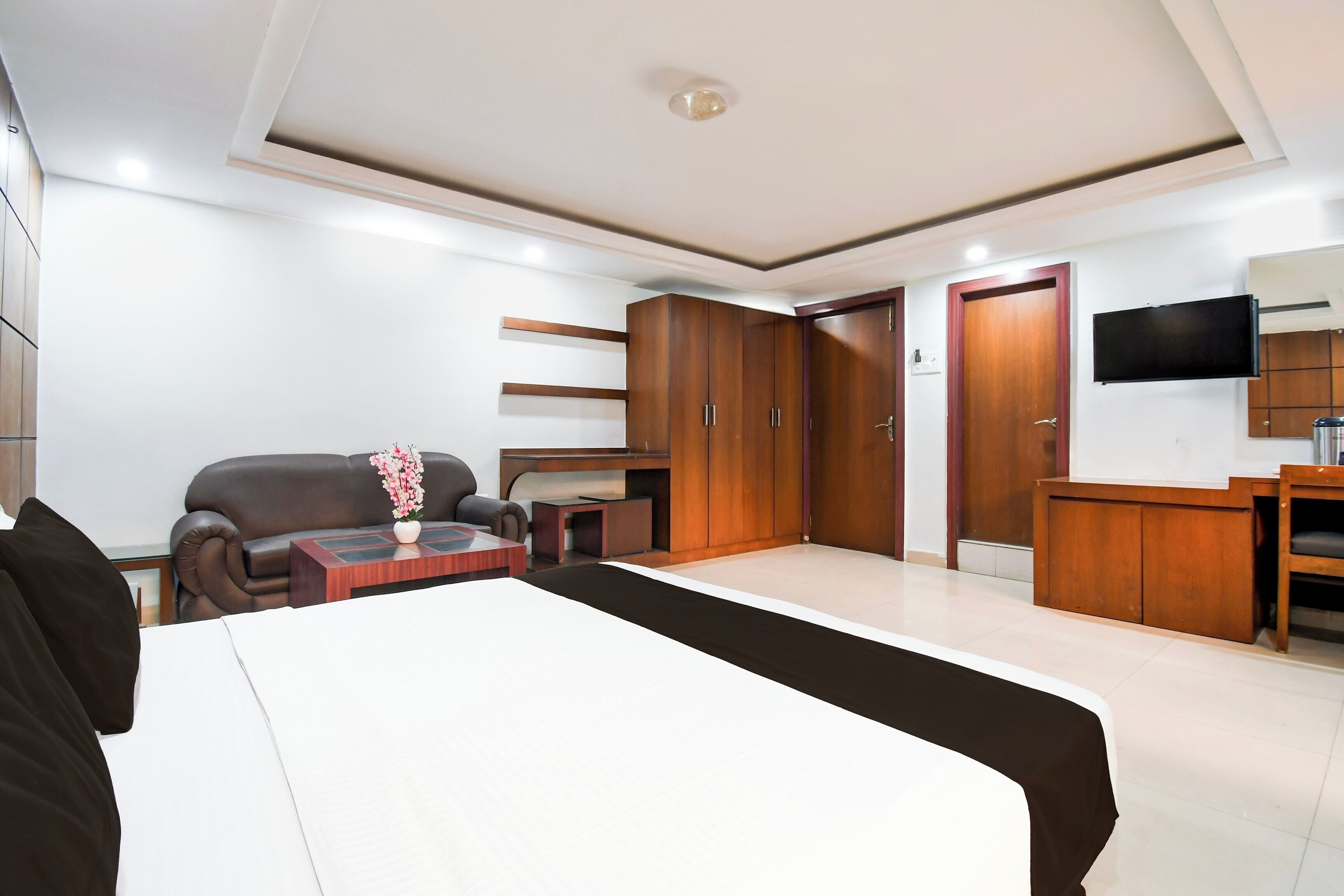 A hotel room with a bed, a sofa, a TV, and a wardrobe.