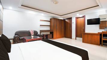 A hotel room with a bed, a sofa, a TV, and a wardrobe.