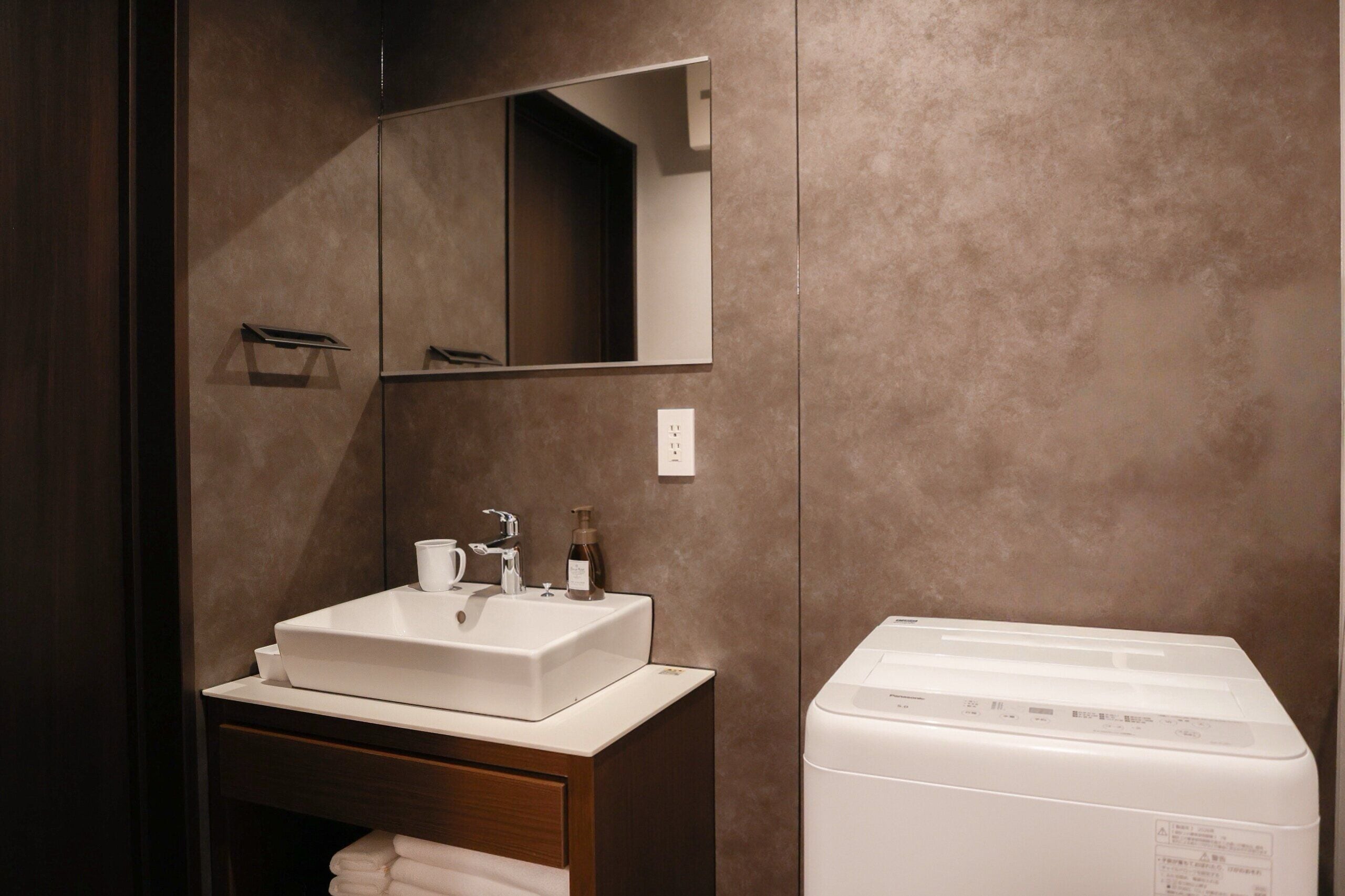 A bathroom with a white sink, a mirror, a towel rack, and a white washing machine.