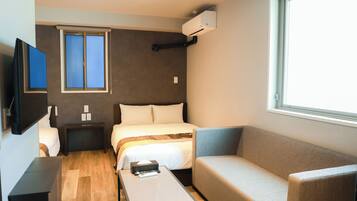 Habitación de hotel compacta con cama, sofá, televisión, ventana y aire acondicionado.