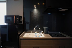 Una cocina equipada con microondas, lavabo y hervidor.
