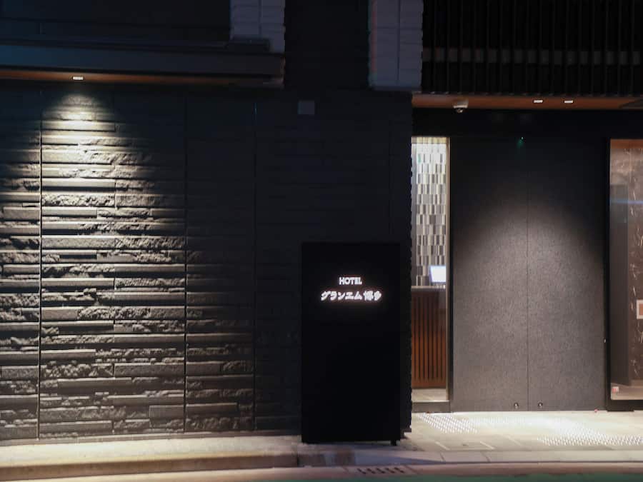 A hotel entrance with a stone facade, a digital display sign, and an elevator.