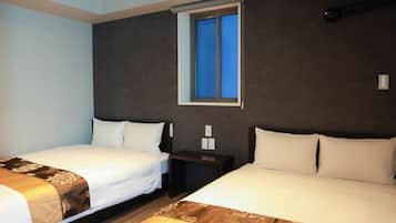 A hotel room with two beds, a window, and a nightstand with a lamp.