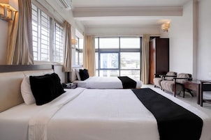Habitación de hotel con dos camas, un escritorio y vistas a la ciudad.