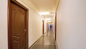 Un pasillo de hotel con puertas de madera, piso de baldosas y un largo corredor que lleva a una habitación.