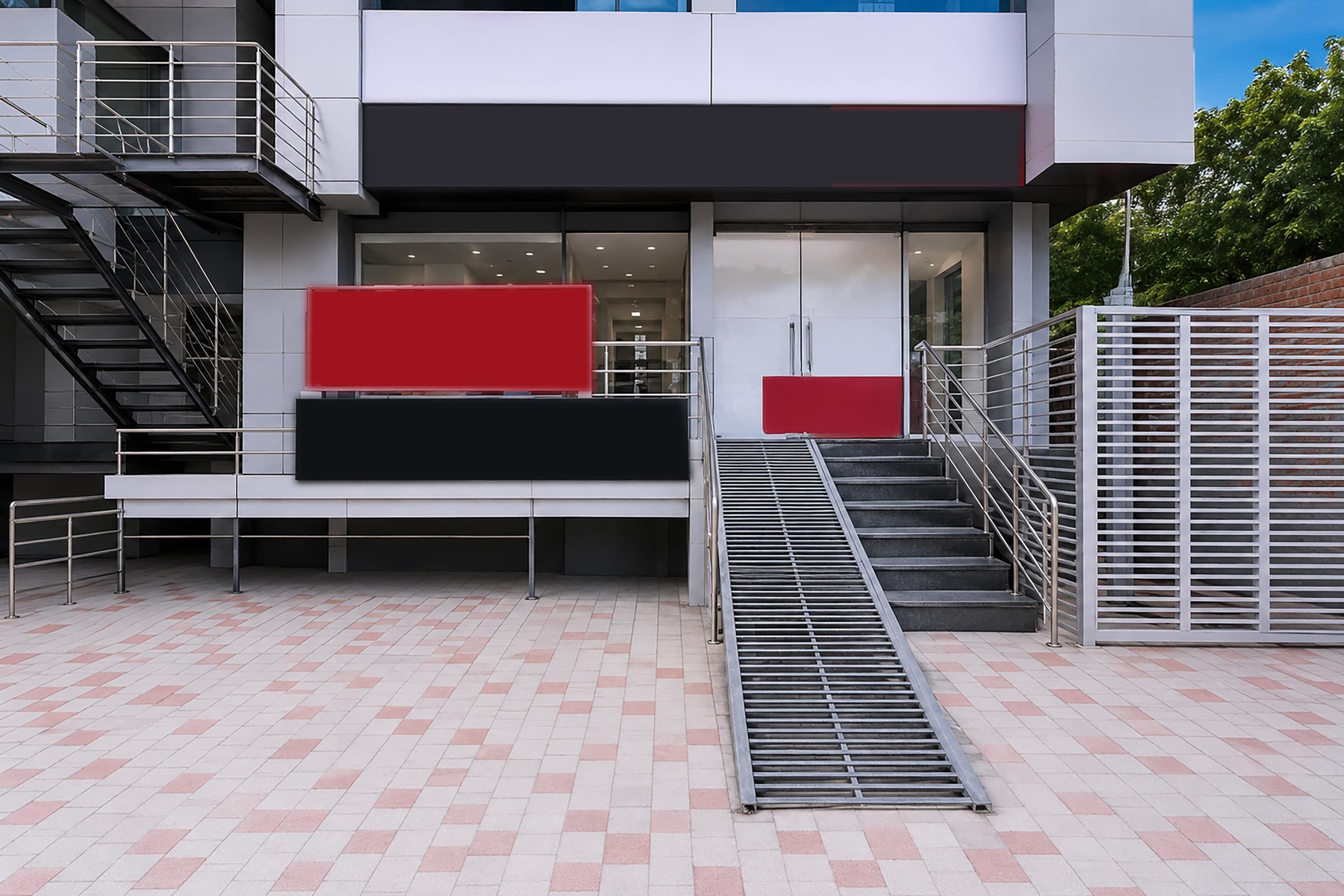 A modern building with a staircase, a red and black panel, and a metal railing.