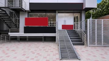 A modern building with a staircase, a red and black panel, and a metal railing.