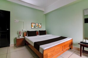 A hotel room with a single bed, a nightstand with a vase of flowers, and a wall-mounted power outlet. - Super Collection O Jalpaiguri Formerly (Jalpaiguri)