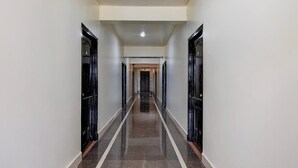 Un long couloir étroit, avec des portes de part et d’autre, qui mène à une pièce au bout.