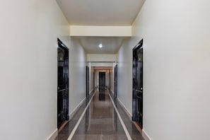 A long, narrow hallway with doors on both sides, leading to a room at the end.