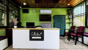 Un comptoir d’accueil avec une pancarte indiquant qu’il est géré par l’entreprise, une horloge, un tableau encadré et un mur vert.