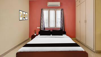 A bedroom with a bed, a window with curtains, an air conditioner, and a wardrobe.