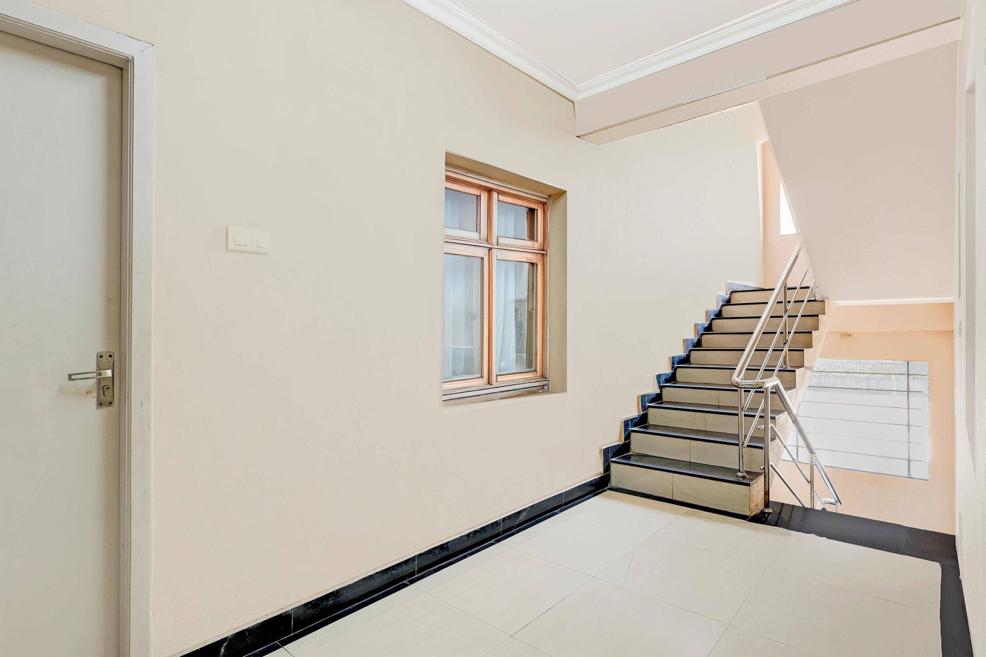 Un couloir avec une porte, une fenêtre et un escalier.