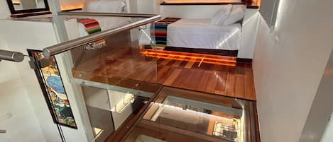 A compact room with a bed, a glass partition, and a small kitchen area.