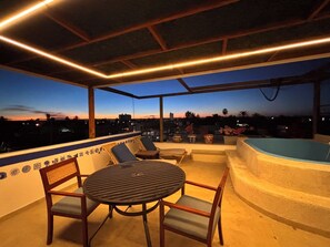 An outdoor seating area with a table and chairs, a hot tub, and a view of the cityscape at dusk. - Superb 6-bedroom Full House with AC in vibrant La Paz (La Paz)