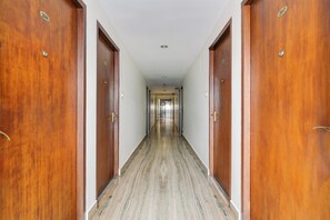 A long, narrow hallway with wooden doors on either side and a marble floor.