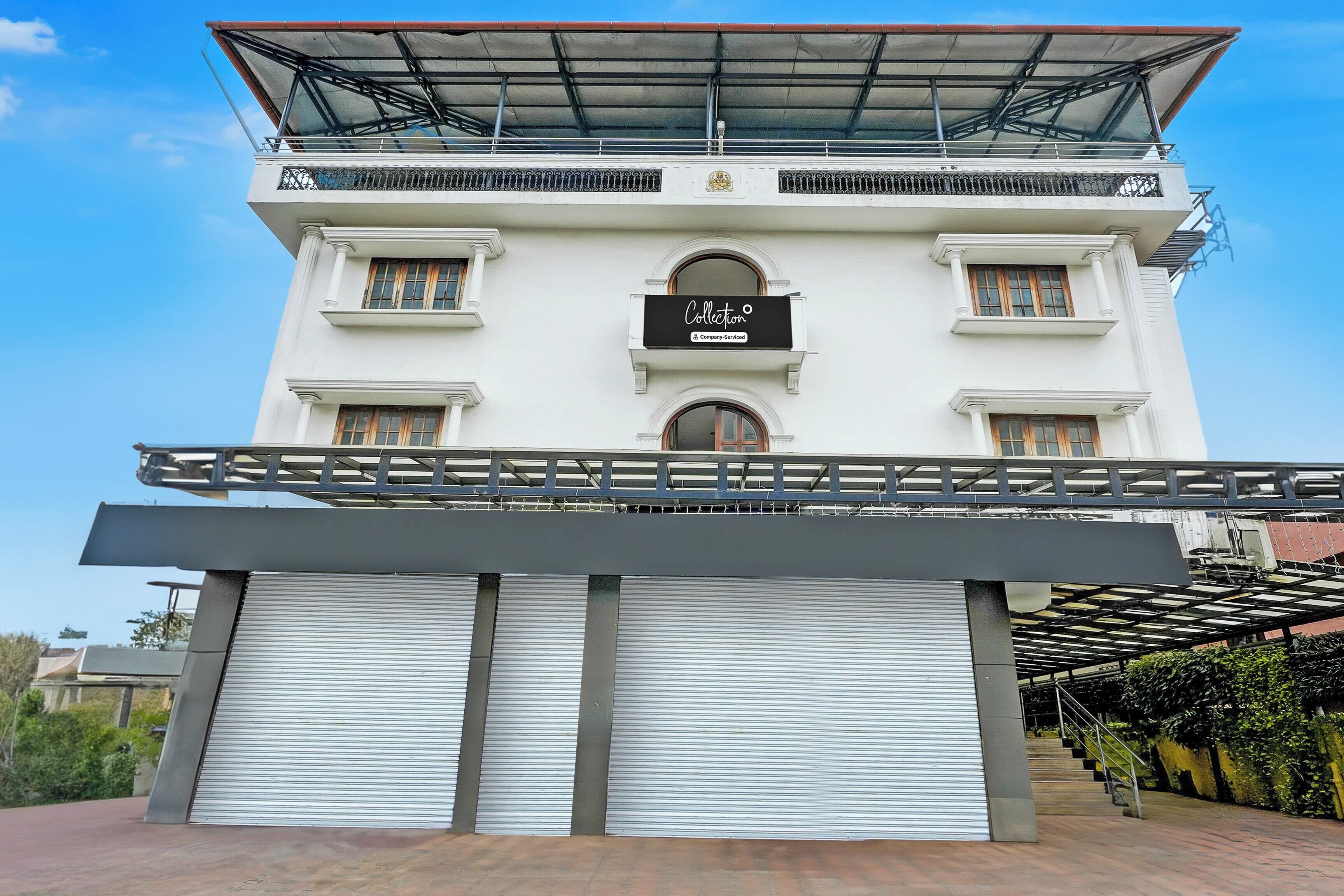A building with a white facade, a black sign with the word 'Collection,' and a covered entrance with a metal railing.