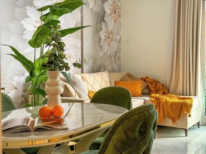 A modern living room with a glass coffee table, a sofa with patterned cushions, a green armchair, and a large potted plant. - Qoople Legend 36 В-04 100 Meter vom Strand entfernt by Interhome (Alanya)