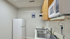 A compact kitchen with a built-in microwave, a stainless steel sink, and a small refrigerator. - Clemson Basecamp! Lake Keowee Hideaway (Seneca)