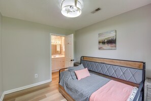 Ein Schlafzimmer mit Bett, Nachttisch, einem Gemälde und einer Tür zu einem Badezimmer.