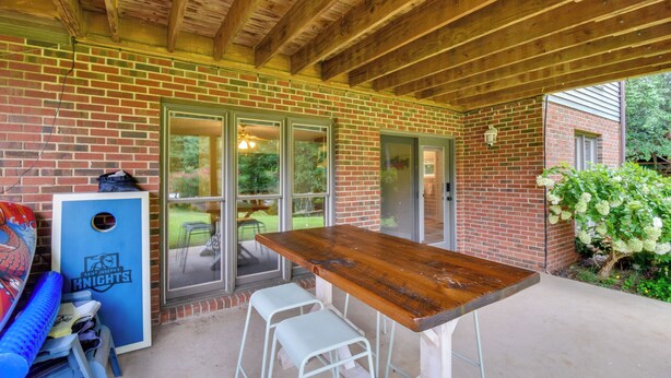 A covered patio area with a wooden table and two white metal stools. - Clemson Basecamp! Lake Keowee Hideaway (Seneca)