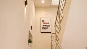 A staircase with wooden steps, a metal handrail, and a wall-mounted light fixture. - KU Residency (Varanasi)