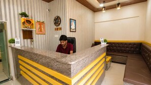 A reception area with a marble counter, a reception desk, a sofa, and a chandelier. - KU Residency (Varanasi)