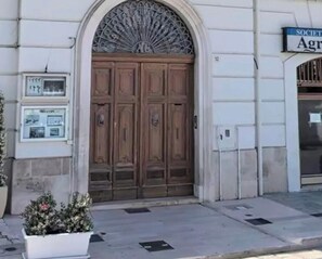 Um edifício com entrada central, uma varanda com balaústres brancos e uma placa indicando uma sociedade.