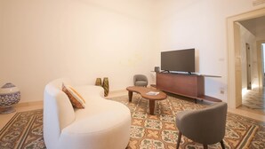 Ein modernes Wohnzimmer mit einer Couch, einem Sessel, einem Couchtisch und einem Flachbildfernseher auf einer Holzkommode.