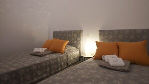 Ein Hotelzimmer mit zwei Betten, jeweils mit Kissen und einem gefalteten Handtuch mit 'TD'.