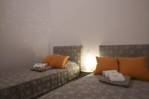 A hotel room with two beds, each with a pillow and a folded towel with 'TD' on it. - TD Palazzo Fiume 1 Heart of Polignano (Polignano a Mare)