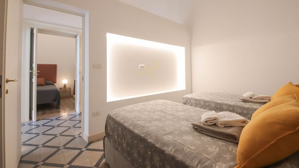 Ein Hotelzimmer mit zwei Betten, einem großen Fenster und einer Tür zu einem anderen Raum.