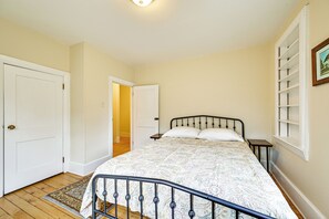 Ein Schlafzimmer mit einem Bett, einem Nachttisch, einer Tür und einem Fenster mit Jalousien.
