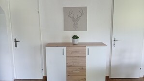 A room with a wooden cabinet with drawers, a small potted plant on top, and a wall-mounted artwork of antlers. - Apartment 'Weidenblick' with Mountain View, Private Terrace and Wi-Fi (Schottwien)