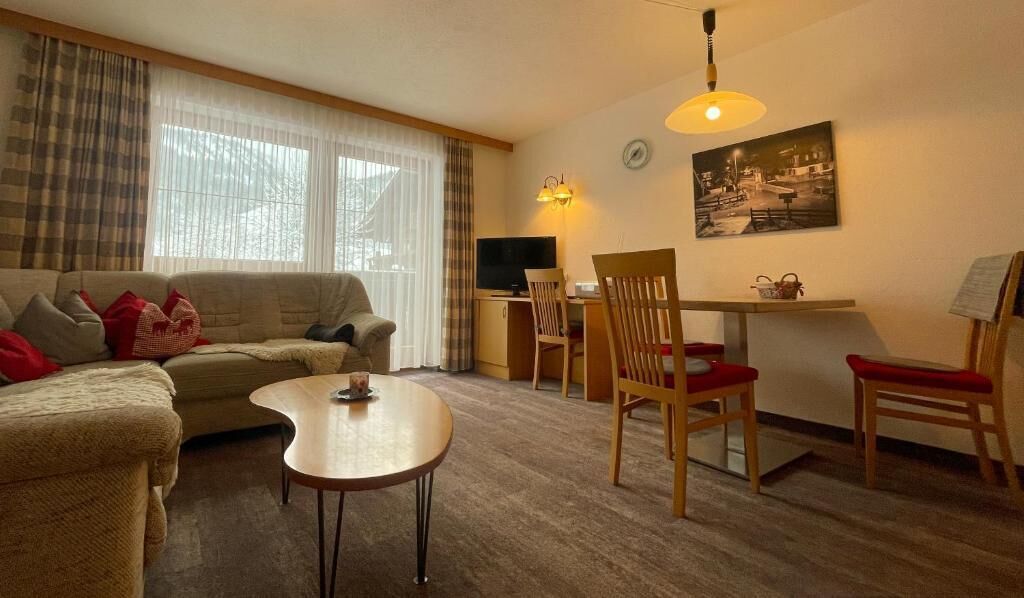Ein gemütliches Wohnzimmer mit einer Couch, einem Couchtisch und einem Essbereich mit Stühlen und einem Tisch.