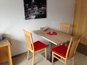 A dining table with four wooden chairs, a basket, and a placemat. - Ferienwohnungen Tannheim - Martina Fügenschuh (Tannheim)