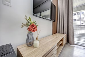 Ein modernes Wohnzimmer mit einem Holzkonsolentisch, einer Blumenvase, einer Kerze und einem an der Wand befestigten Fernseher.