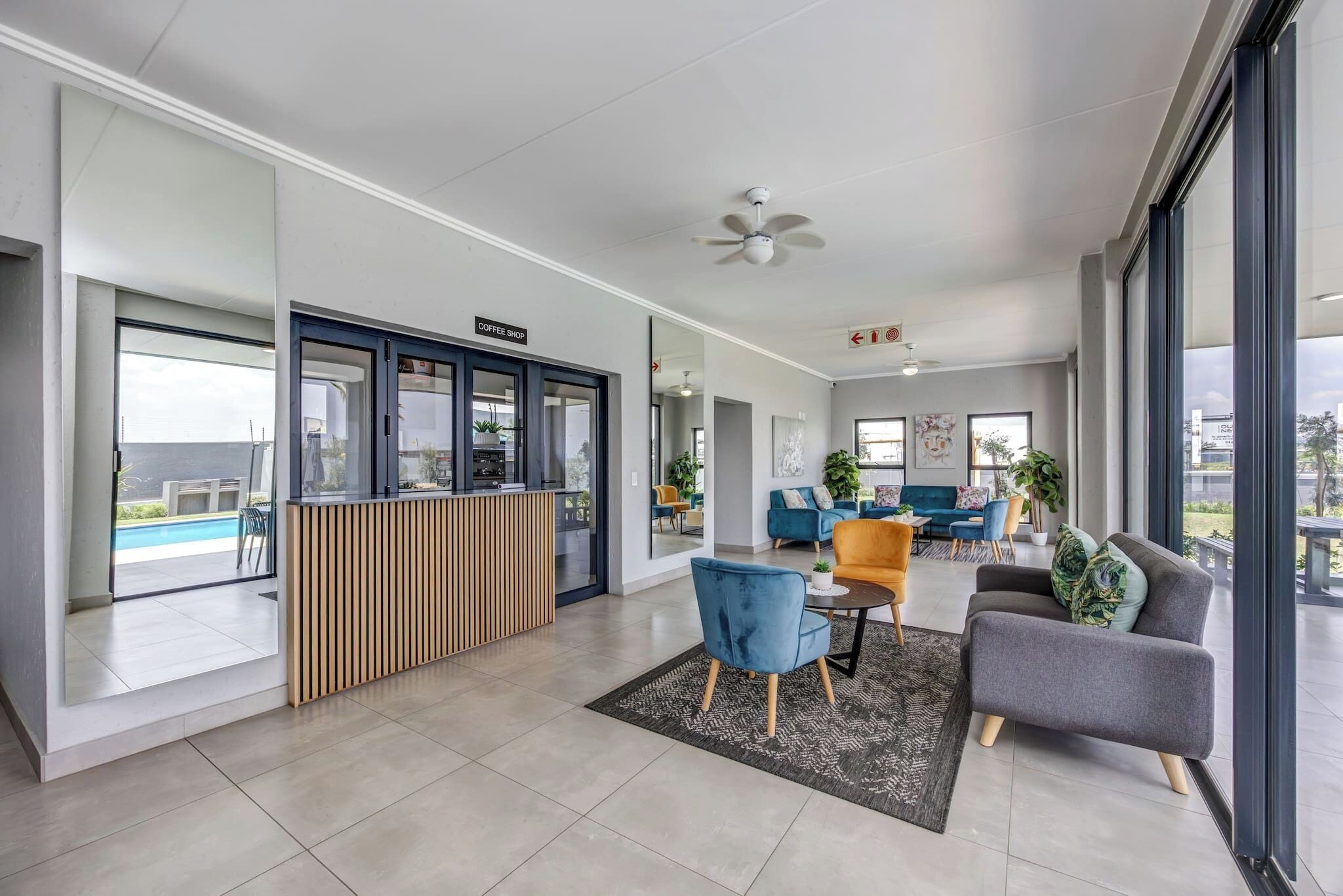 A modern interior with a coffee shop counter, seating area with sofas and chairs, and large windows offering views.