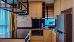 A compact kitchen with wooden cabinets, a built-in microwave, and a Samsung refrigerator. - Luxurious 2BR Condo with Ocean Views in Choeng Thale (Tambon Choeng Thale)