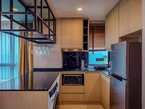 Eine kleine Küche mit Holzausstattung, einer integrierten Mikrowelle und einem Samsung-Kühlschrank.