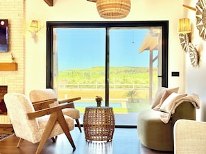 A modern living room with a large sliding glass door leading to a scenic outdoor view.