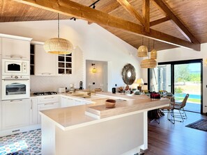 Cozinha moderna com armários brancos, uma ilha central e uma área de jantar com vista.