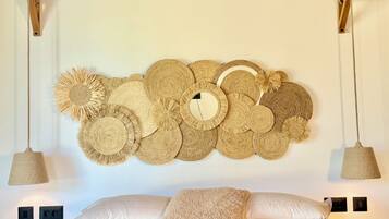 Una cama con un tapiz de pared grande tejido, dos lámparas colgantes y un cojín mullido.
