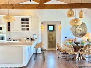 Una cocina moderna con una isla central, vigas de techo de madera y lámparas colgantes de mimbre.