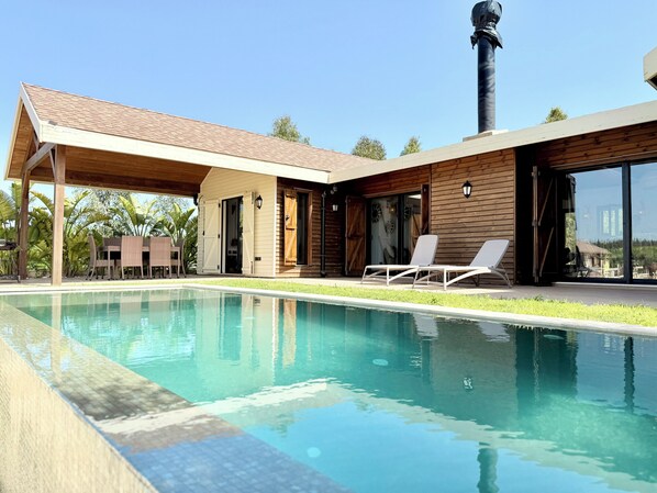 Uma casa moderna com piscina, fachada de madeira e chaminé.