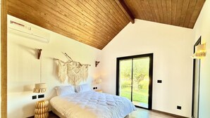 A bedroom with a large bed, wooden ceiling, macramé wall decor, and a sliding glass door to a garden. - Kenz Essia Luxury countryside escape near Tunis (Chaouat)