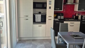 A modern kitchen with built-in appliances, a dining area with a table and chairs, and a view of the outside. - Elegant Guest Room Retreat in West Midlands (West Midlands)