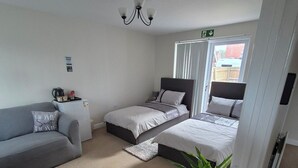A bedroom with a bed, a sofa, a small table with a kettle, and a potted plant. - Elegant Guest Room Retreat in West Midlands (West Midlands)