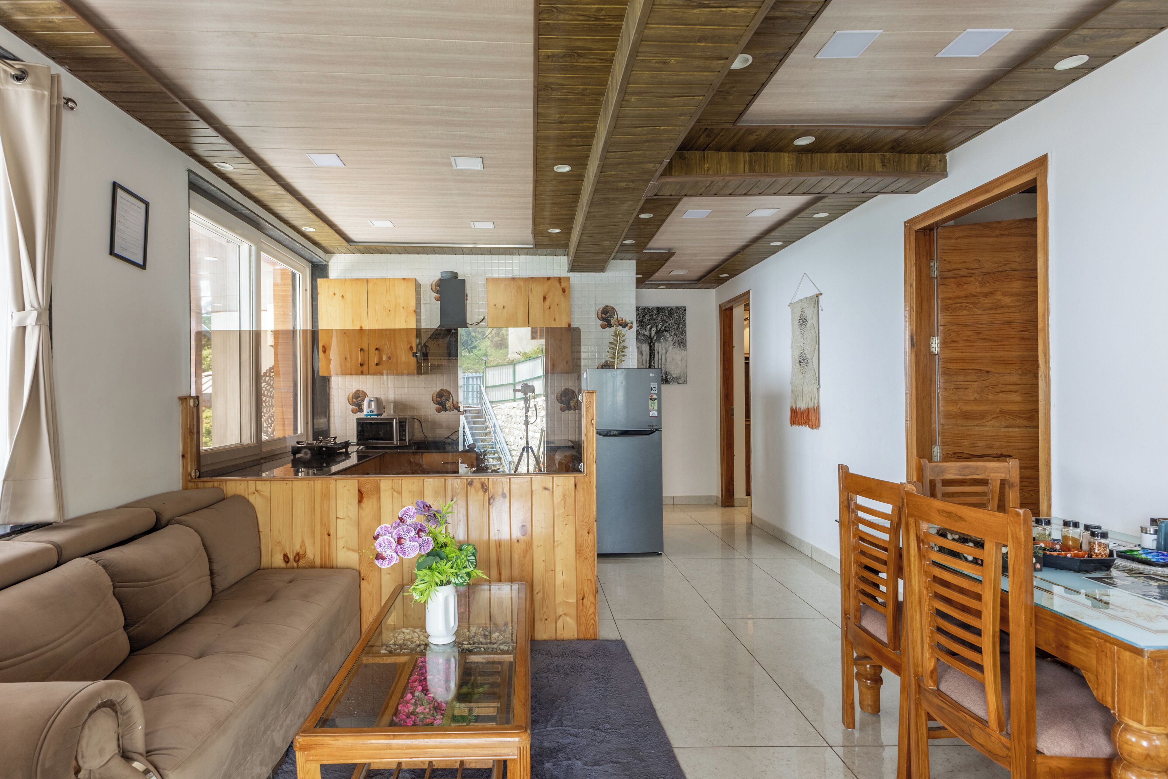 Una cocina moderna con armarios de madera, un refrigerador y un comedor con mesa y sillas.