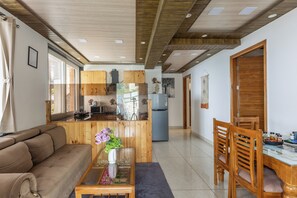 A modern kitchen with wooden cabinets, a refrigerator, and a dining area with a table and chairs.